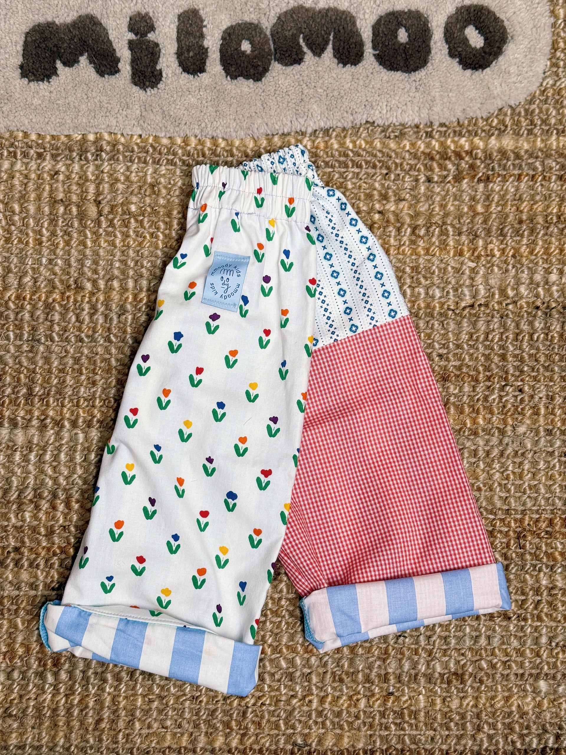Children's pants with floral and checkered patterns on a textured surface